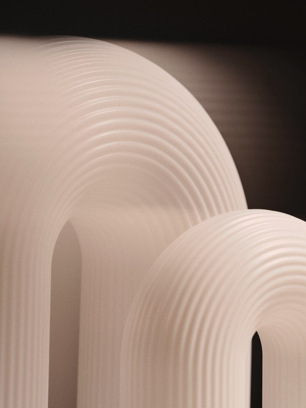 Close-up of the ribbed arched forms of two lamps in white