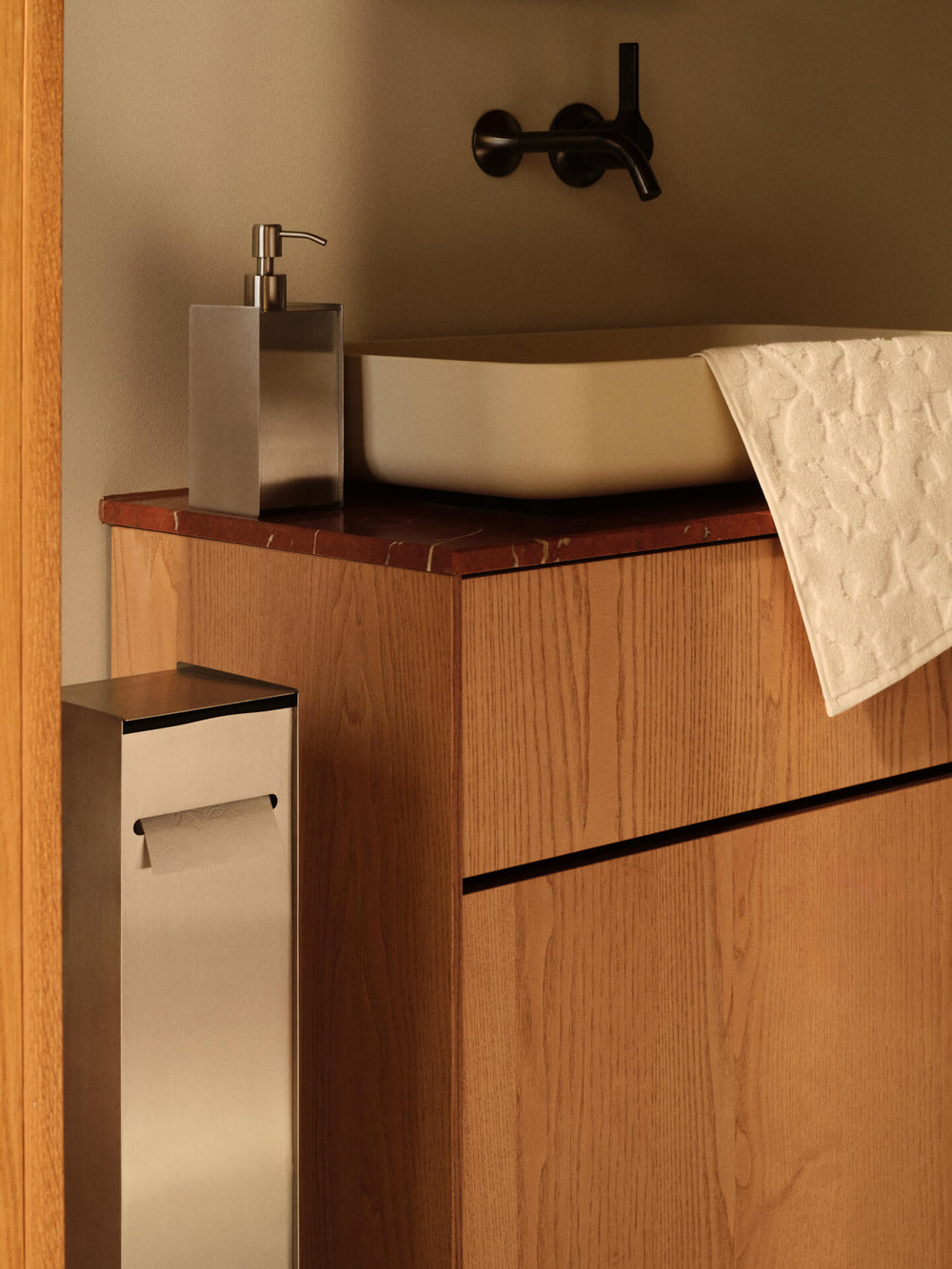 Bathroom with the toilet paper dispenser beside a vanity unit, soap dispenser and towel at the basin