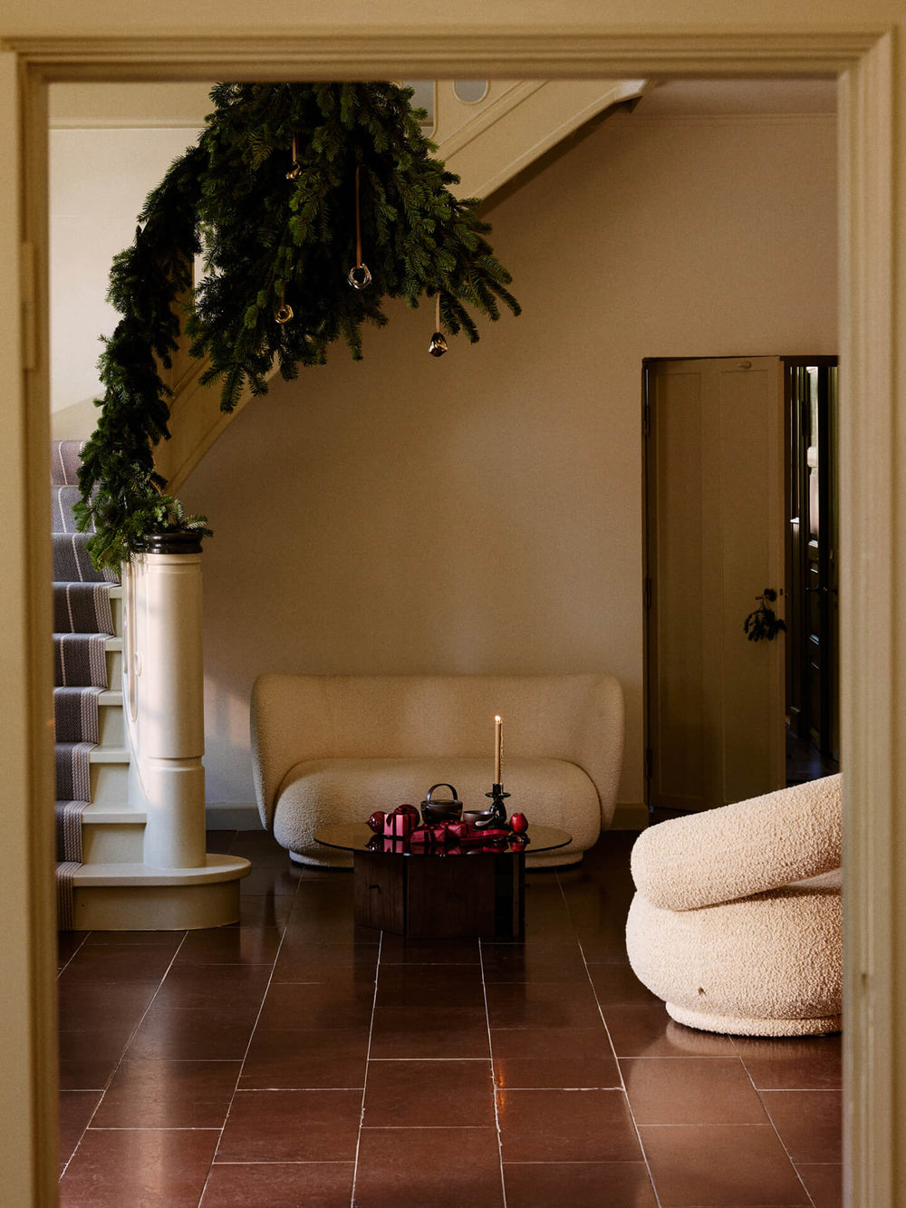Hallway with the ornaments hung on a garland along the staircase, sofa and round table