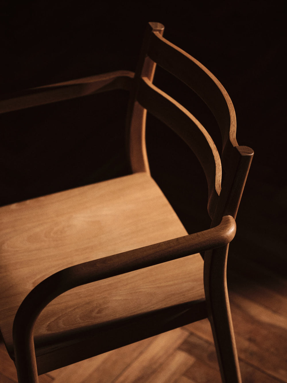 Close-up of the curved armrest joint and double-rail backrest in warm light
