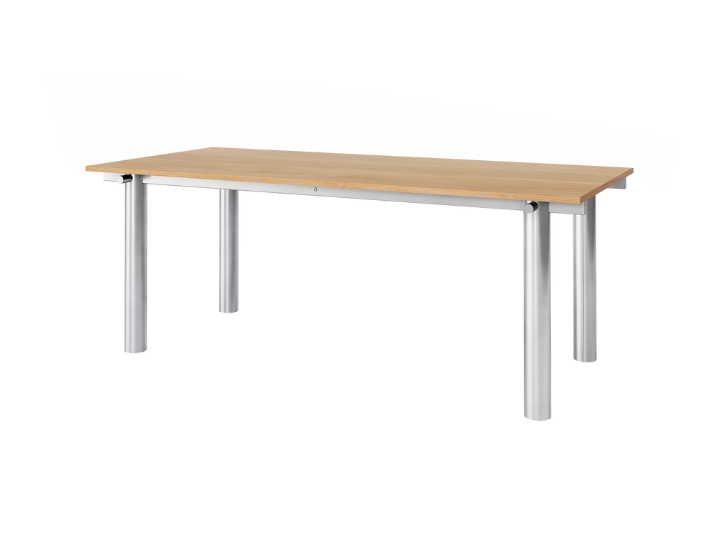Dining table seen at an angle, brushed steel frame with cylindrical legs and oak top