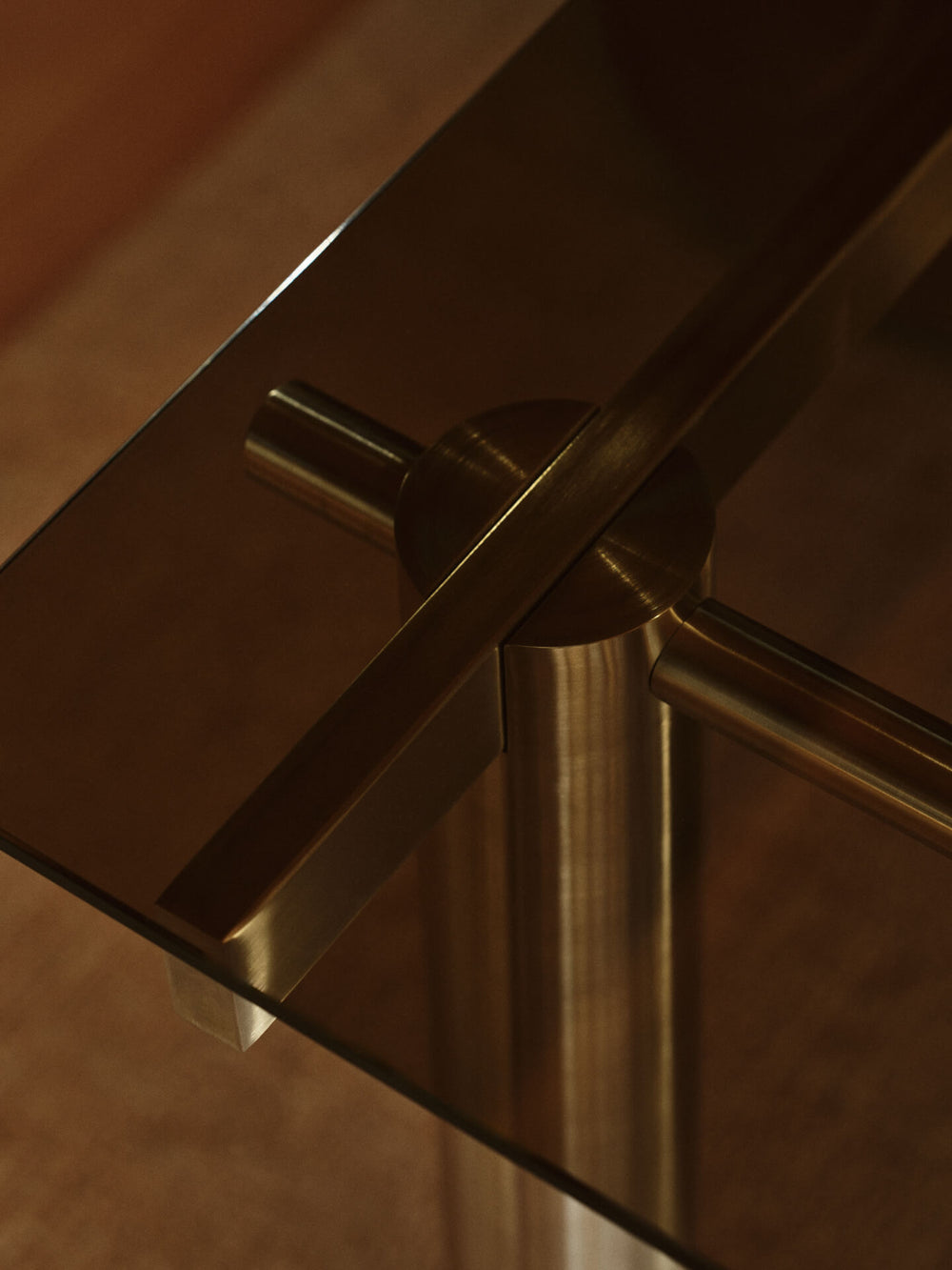 Close-up of the tinted glass top meeting the brushed stainless steel frame joint